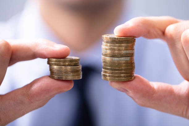 Man Holding Two Coin Stacks To Compare - sales compensation management software